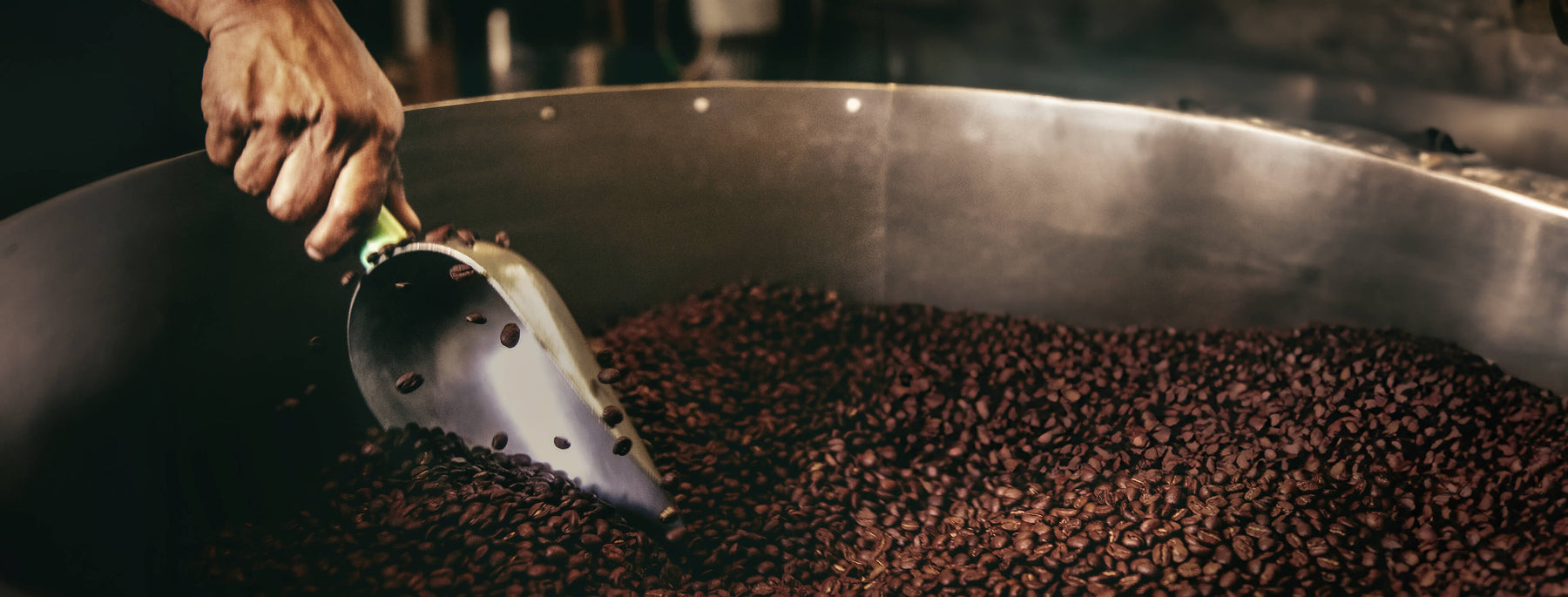 About Us -- scoop going through bin of roasted coffee beans