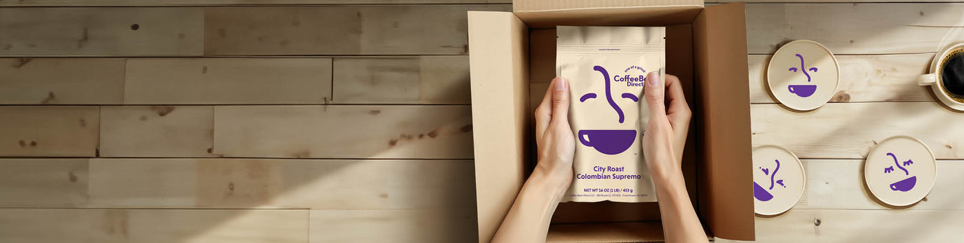 Gift Subscription hero -- customer opening box with new rebrand coffee bag alongside coasters and coffee mug