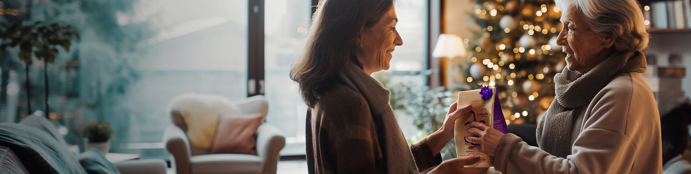 Gift Subscription hero -- woman receiving Coffee Bean Direct coffee gift with a Christmas tree in the background