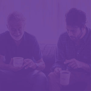 Father's Day and Gift Subscriptions mobile hero with purple overlay -- father and son sitting on a couch enjoying mugs of coffee in our Coffee Bean Direct mugs