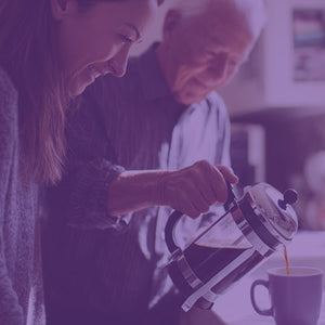 Grandfather's Blend featured mobile hero -- Grandfather pouring cup of coffee into a mug from a French press, alongside his granddaughter in a kitchen setting