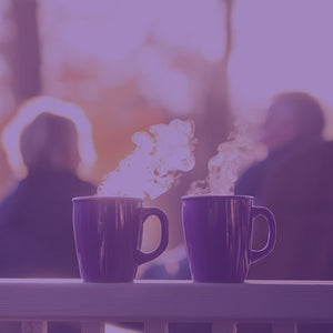 Grandfather's Blend Sale featured mobile hero -- Two purple mugs with steam on a table outdoors with two people sitting in the background