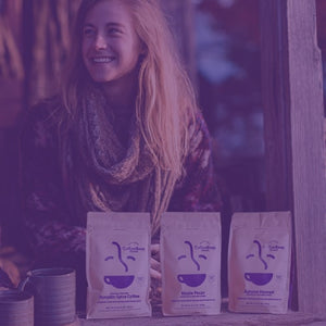 Pumpkin Spice & Everything Nice GIft Bundle featured mobile hero -- Two women sitting in front of a house enjoying cups of coffee alongside Coffee Bean Direct coffee bags