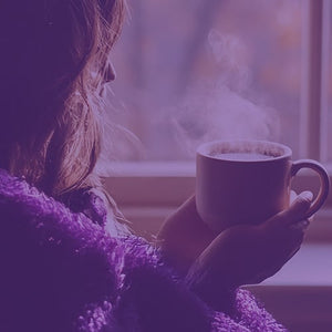 Roaster's Blend Subscription featured hero -- a woman wearing purple enjoying a hot cup of coffee by the window sill