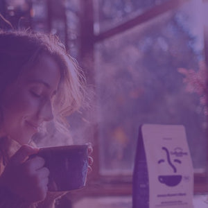 Roaster's Blend Subscription featured mobile hero -- Woman holding a cup of coffee with a bag of Roaster's Blend in the background