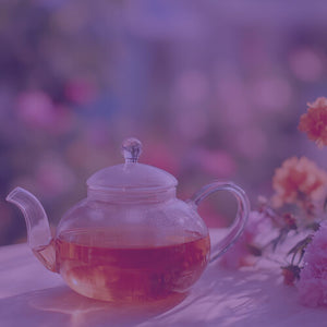Summer Blossom Herbal Tea featured hero -- teapot on a table filled with Summer Blossom tea alongside bright flowers