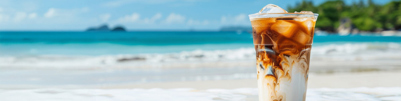 Mocha Mudslide featured hero -- cup of iced coffee in the foreground and a tropical beach setting in the background