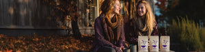 Pumpkin Spice & Everything Nice GIft Bundle featured hero -- Two women sitting in front of a house enjoying cups of coffee alongside Coffee Bean Direct coffee bags