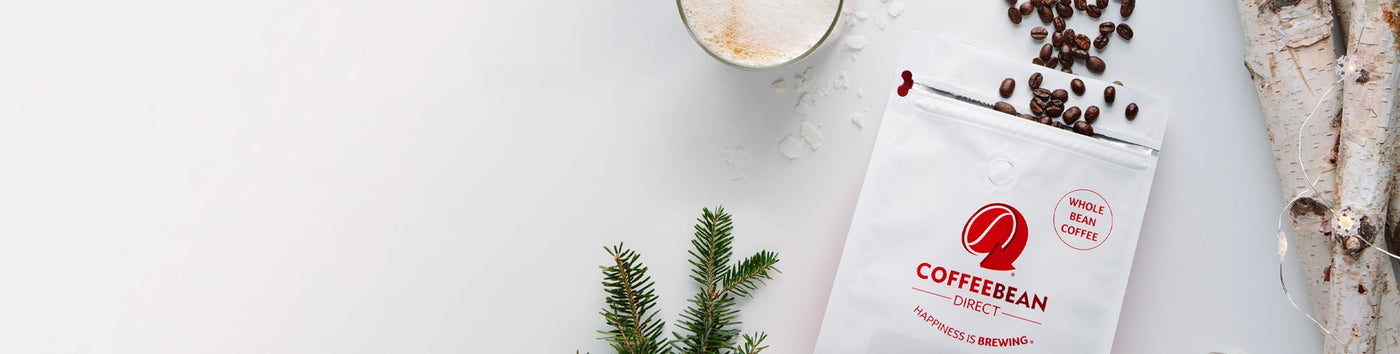 Gift Subscription hero -- opened coffee bag with beans spilling out next to tree bark, mug of coffee, and pine tree leaves