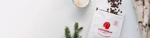 Gift Subscription hero -- opened coffee bag with beans spilling out next to tree bark, mug of coffee, and pine tree leaves