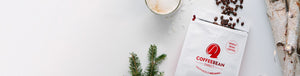 Gift Subscription hero -- opened coffee bag with beans spilling out next to tree bark, mug of coffee, and pine tree leaves