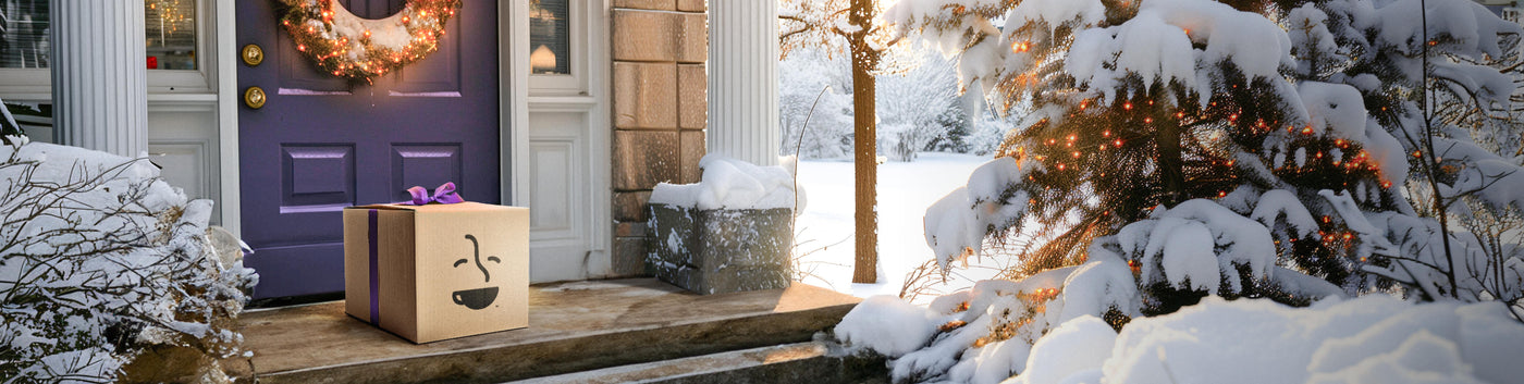 Subscription landing page hero -- Coffee Bean Direct gift package on doorstep of home surrounded by snow-covered trees