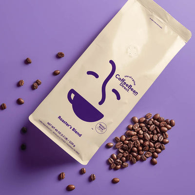 Coffee Bean Direct Roaster's Blend Subscription -- Roaster's Blend coffee bag alongside pile of fresh roasted coffee beans