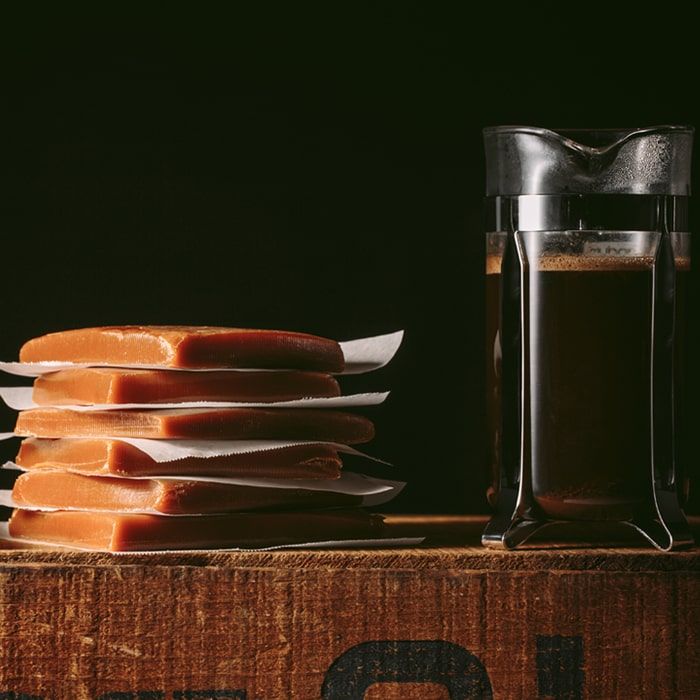 Coffee Bean Direct Caramel Royale flavored coffee -- French Press with coffee alongside a stack of caramel pieces